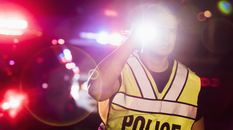 A police officer pointing a bright flashlight toward the camera