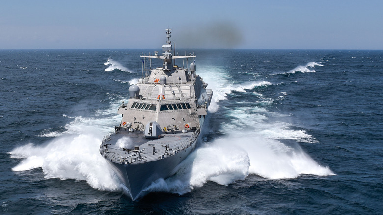The USS Detroit moving through the ocean, white waves in wake