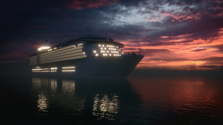 A large cruise ship with lights turned on at the night time in water