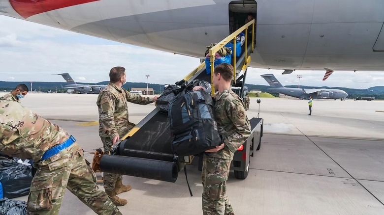 four airmen load supplies aboard a CRAF plane