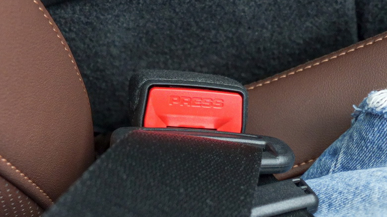 Closeup of a passenger side seatbelt clip with a strip of velcro laying across the "top" of it.
