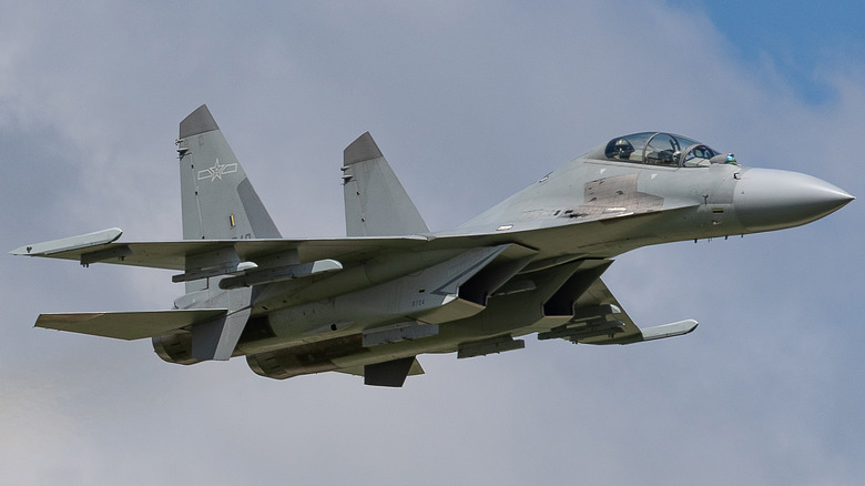 J-16 fighter jet in flight against grey clouds, two tail fins, raised cockpit