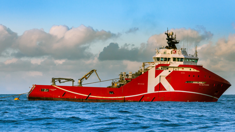 large tug on a calm sea with towing cables behind it