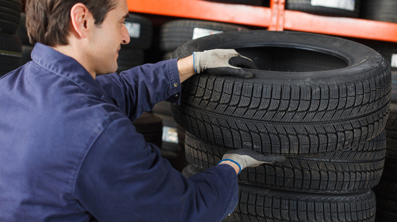 Mechanic lifting a car tire from a stack