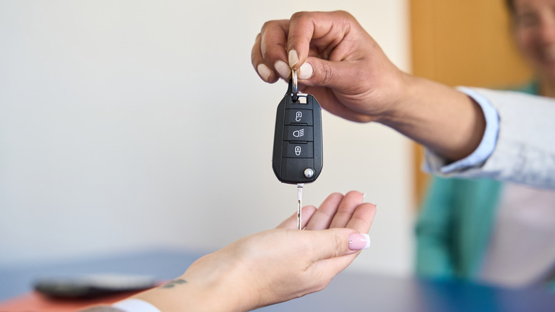 Set of car keys being handed from a seller to a buyer