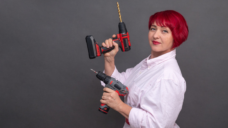 A woman with red hair holding professional-grade power tools