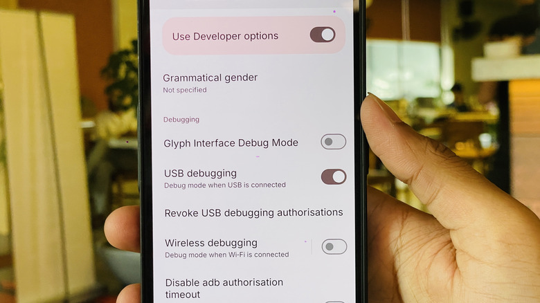 a man holds up android phone with usb debugging enabled