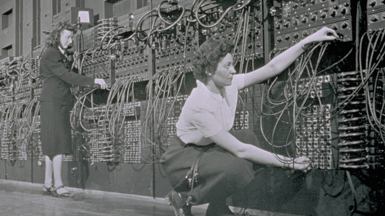 Computer operators program ENIAC, the first electronic digital computer, by plugging and unplugging cables and adjusting switches.