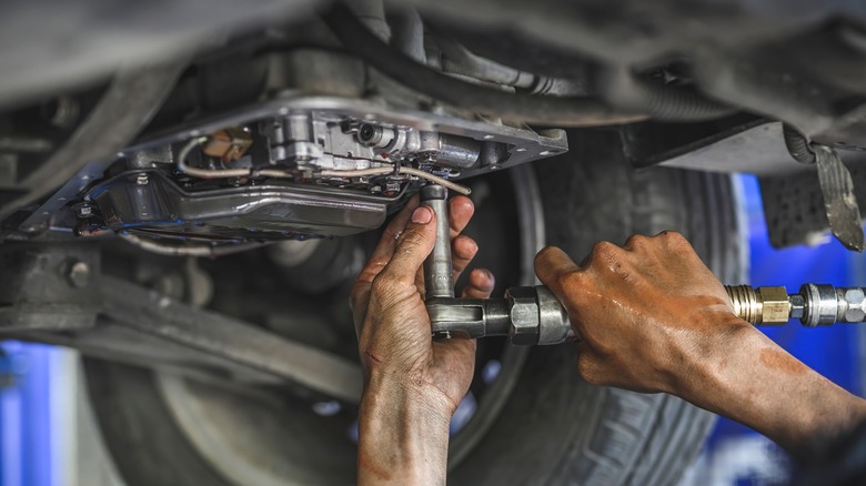 Close up of a mechanic's hand screwing a car part