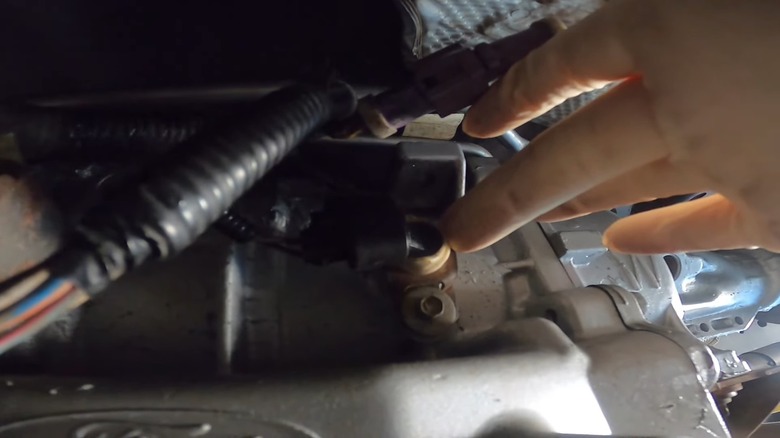A person replacing the output speed sensor on a ford f150 transmission