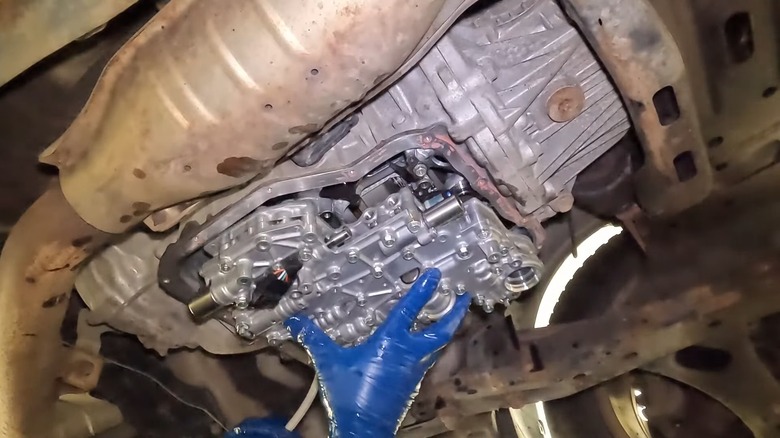 A person installing a new transmission valve body