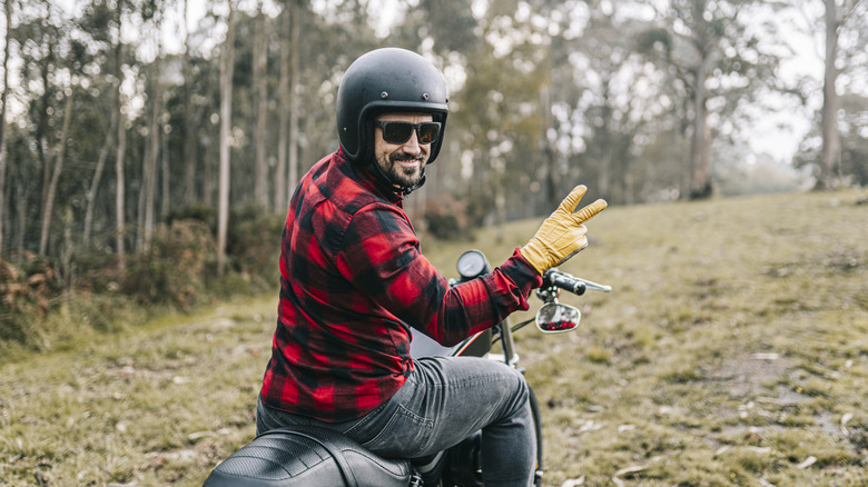 man doing peace sign on motorcycle