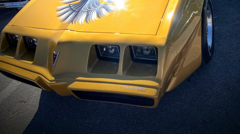 gold Pontiac Firebird with black and silver hood bird emblem