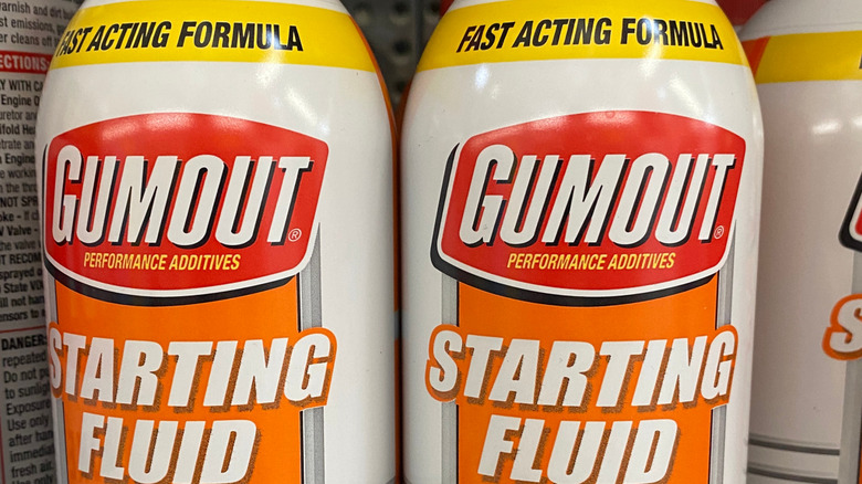 Close-up of several bottles of Gumout-brand starting fluid on store shelves.