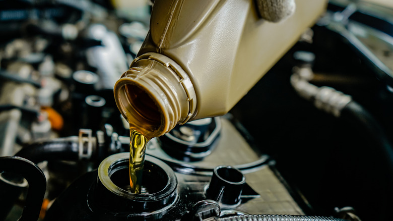 Close-up of mechanic pouring engine oil in a car