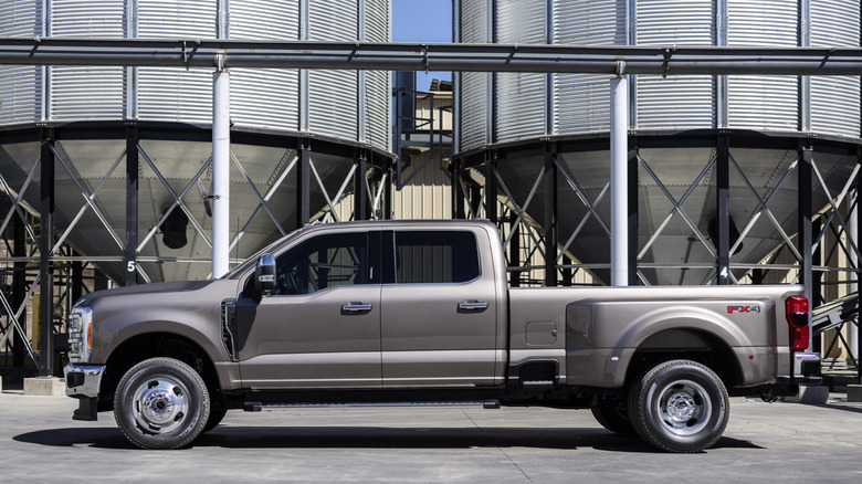 Grey ford F-350 Super duty viewed from left side in front of grain dispensers