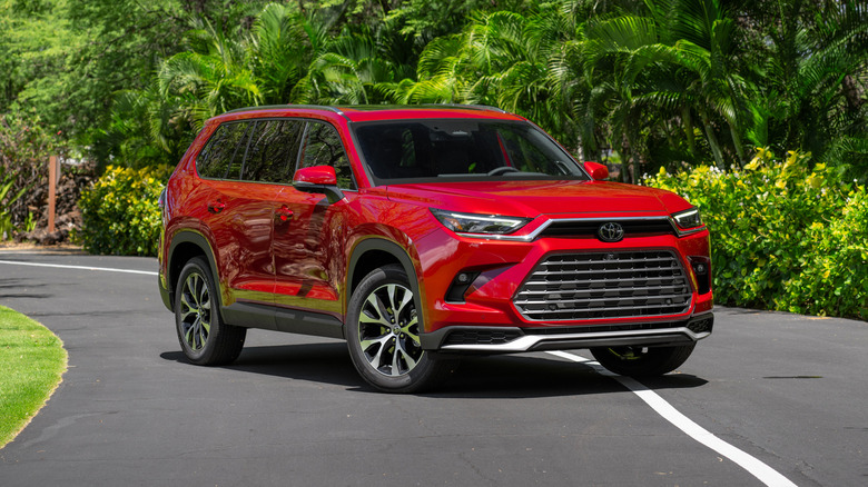 Red Toyota Grand Highlander Platinum parked on a road with trees in the background