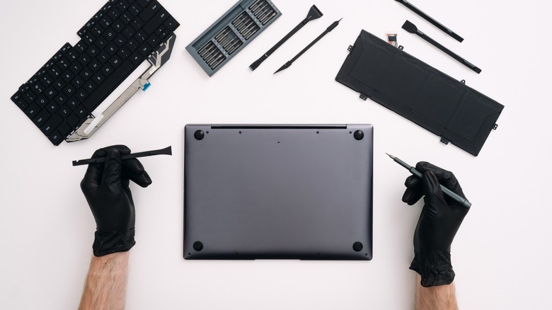 Person opening the back shell of a laptop