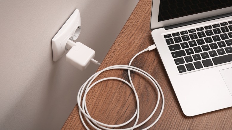 A laptop being charged through a wall outlet