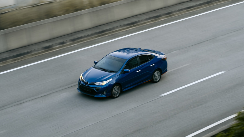 Blue Toyota compact car on a highway, high angle, front 3/4 view