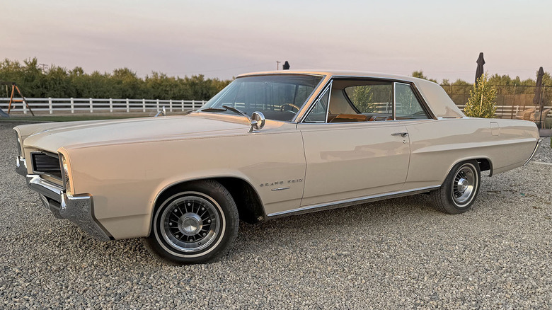 1964 Pontiac Grand Prix with 8 lug wheels parked on asphalt country road