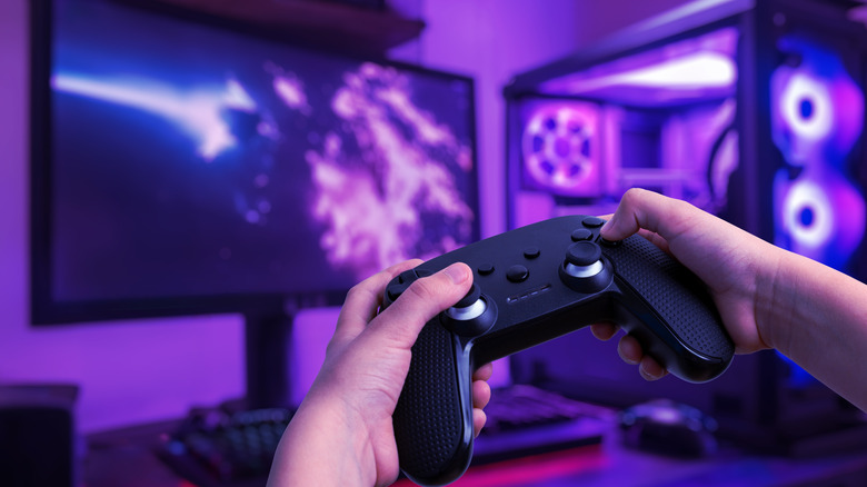 Gaming computer lit with blue LEDs with a controller held in the foreground