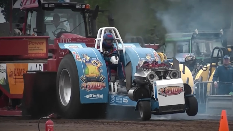 A blue tractor equipped with a Ford GAA V8 pulls of the starting line at a tractor pulling competition