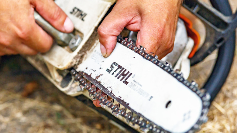 A close up of a man working with a chainsaw
