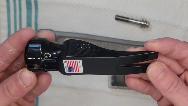 Person rotates the head of a hammer in their hands.