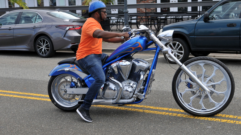 Rider on a blue chopper-style cruiser motorcycle on the street in Freeport Long Island New York.