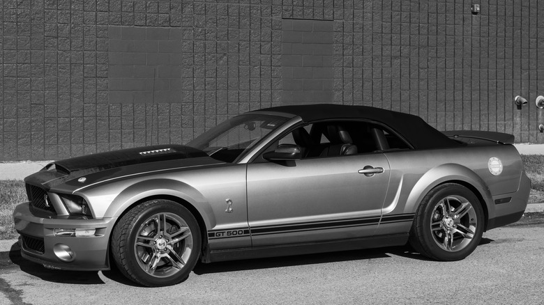 Shelby GT500 convertible parked by a brick wall.