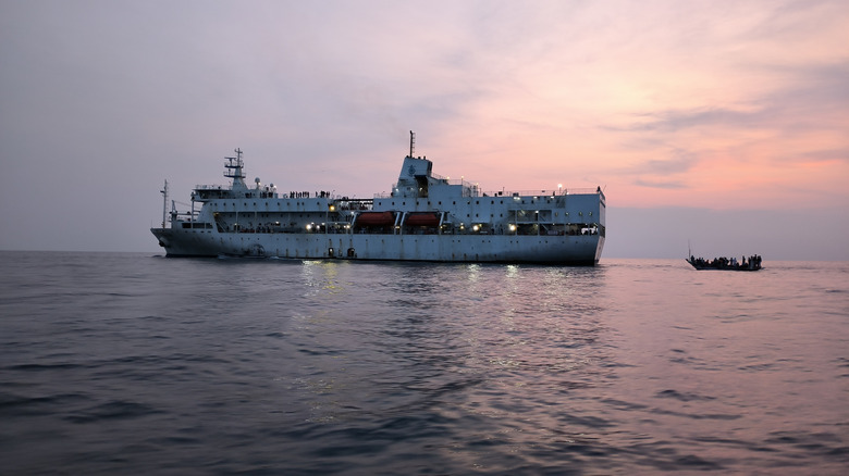 A big passanger ship in the sea with a small boat just behind