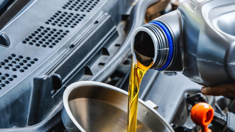 Close up of oil being poured into an engine using a funnel.