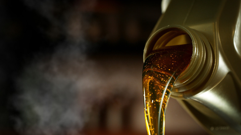 Close-up of engine oil poured from bottle, dark background