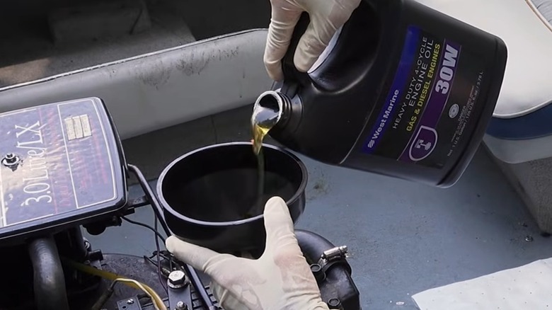A person pouring marine oil into a boat