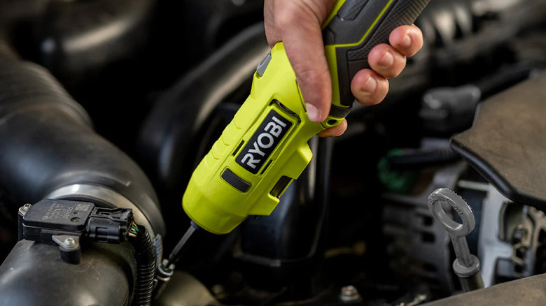 person using Ryobi electric screwdriver on car