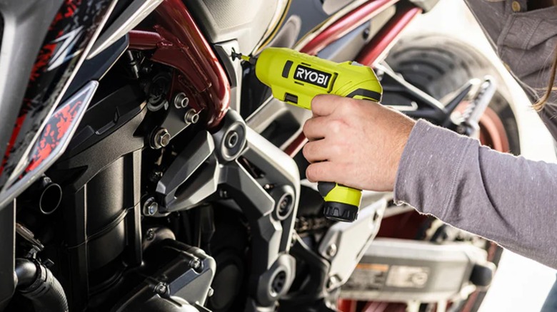 man using Ryobi electric screwdriver on vehicle