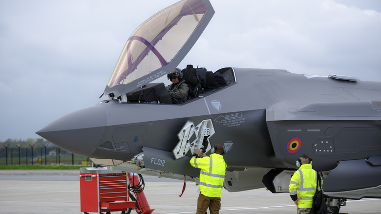 A pilot and technicians work on an F-35 Lightning II fighter jet.