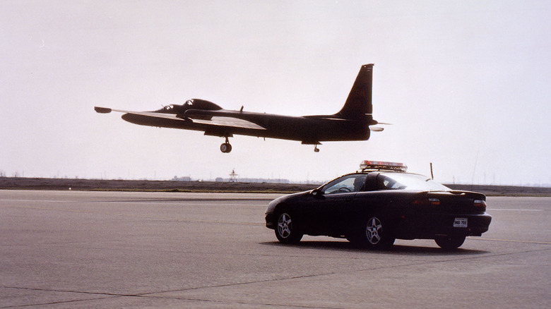 A U-2 landing while a chase car waits on the tarmac for it