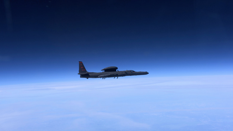 A profile shot of a U-2 flying high in the sky where the the background gradually shifts from blue to black