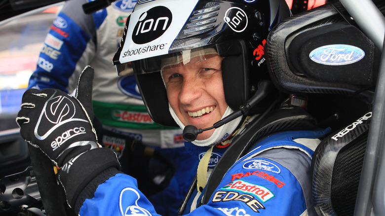 Petter Solberg sitting in driver's seat of rally car giving thumbs-up