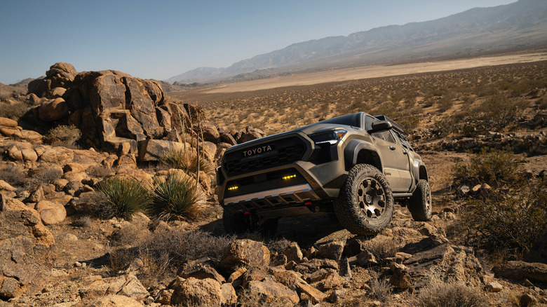 A Toyota Tacoma Trailhunter crawling some rocks, front 3/4 view