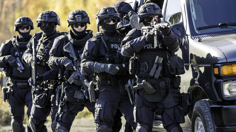 Swat team police raid, officers standing by behind van