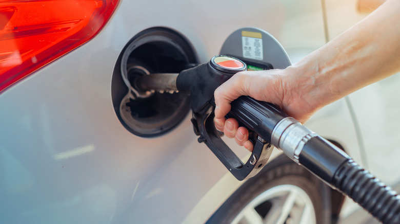 Close-up of hand refueling sedan at a gas station fuel pump