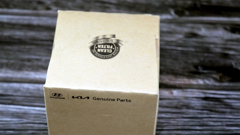 A cardboard product box marked "Genuine Parts" on a wooden benchtop.