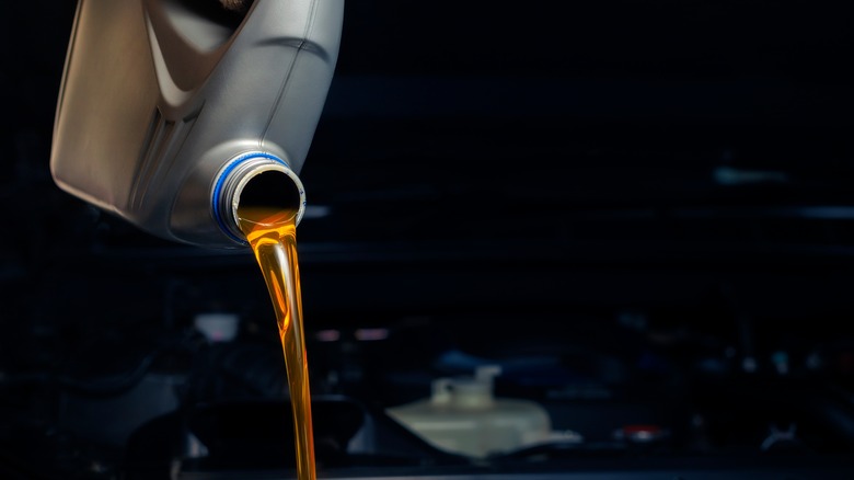 Engine oil being poured out of a grey bottle