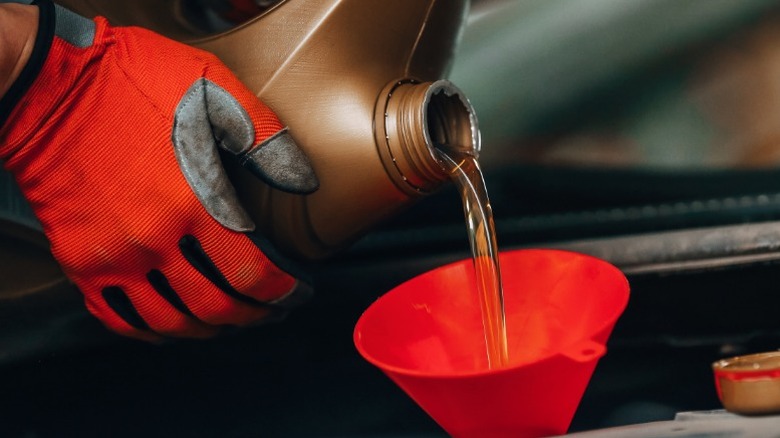 A closeup image of someone filling an engine with oil
