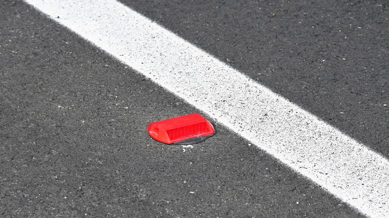 Red road reflector at the edge of a lane