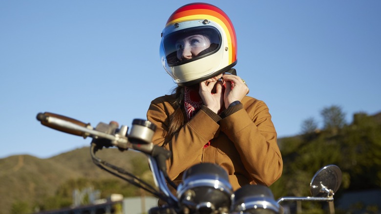A biker adjusting their helmet