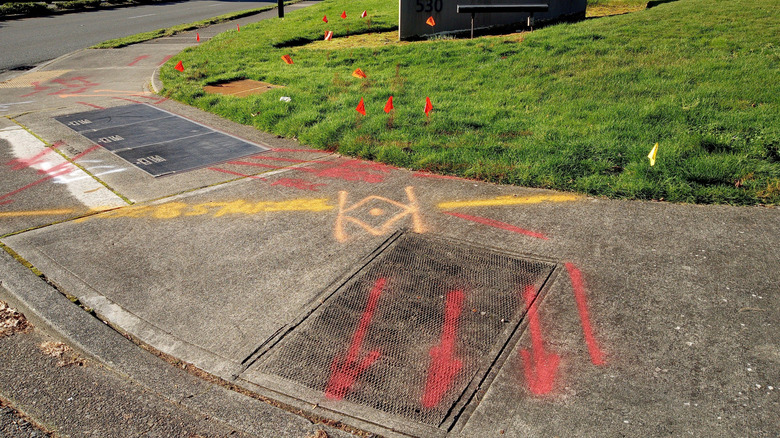 Different colored utility flags and spray paint markings on a street corner indicating where hidden lines are buried.